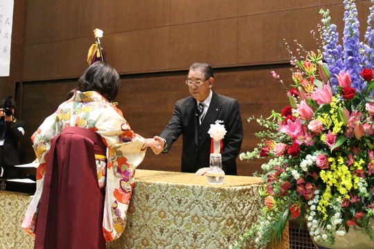 卒業生と固い握手を交わす友田学長